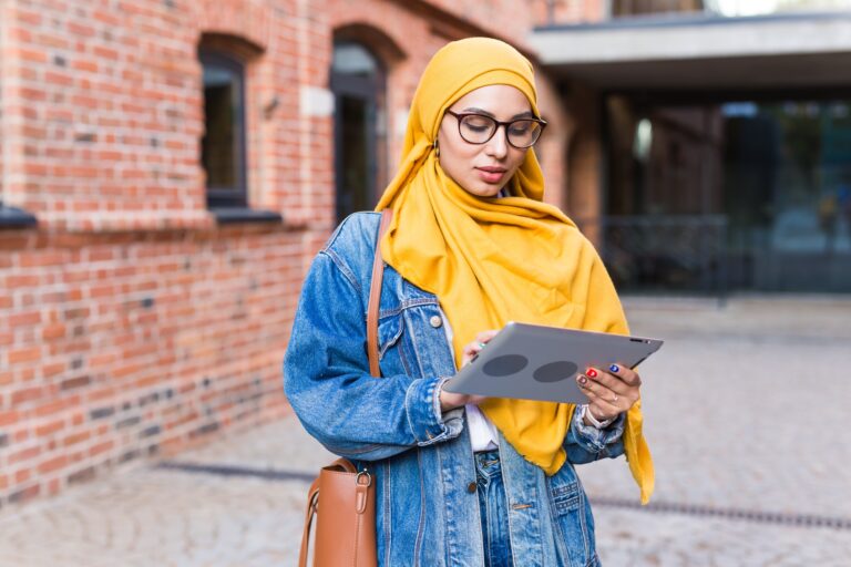 Arab woman student. Beautiful muslim female student wearing bright yellow hijab holding tablet