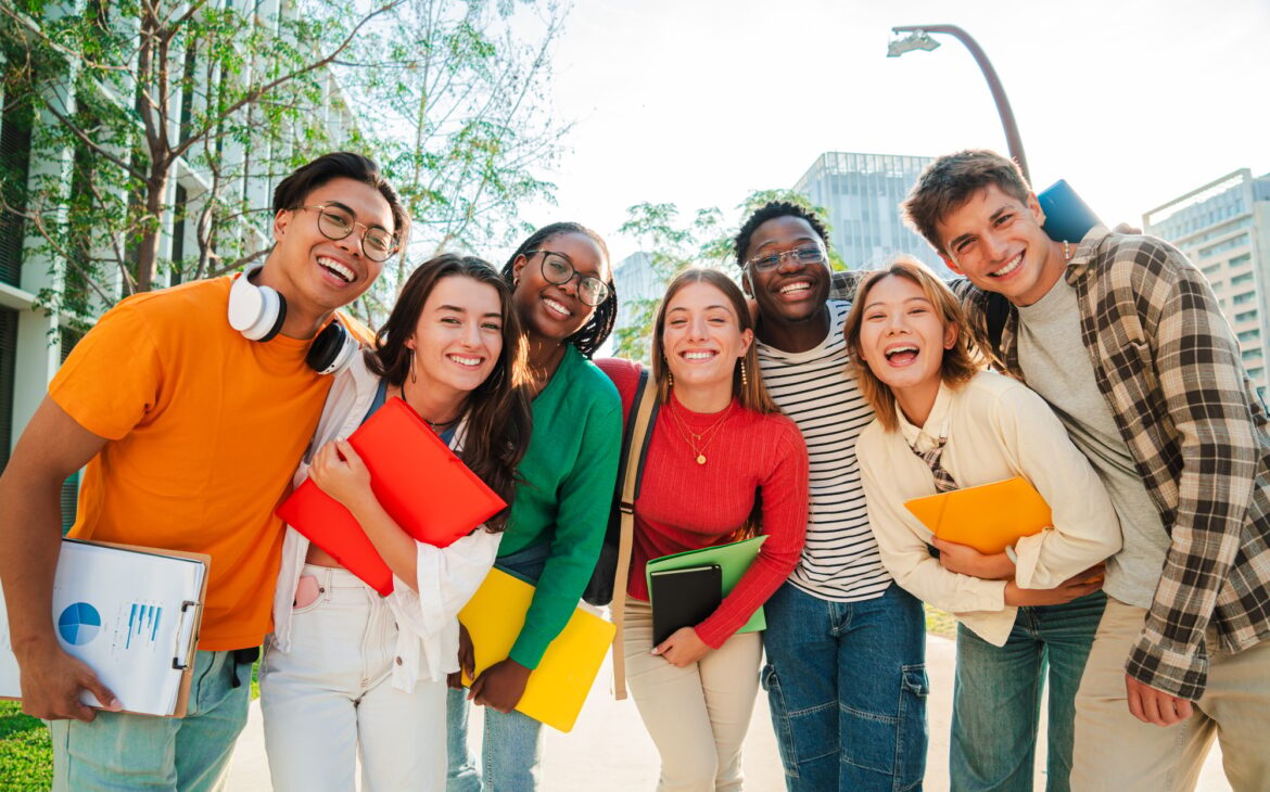 Big group of real students smiling and looking at camera together at high school. Happy teenagers