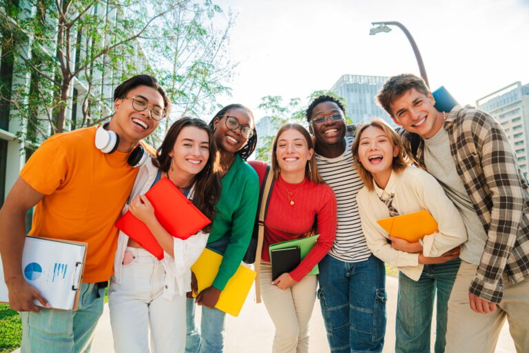 Big group of real students smiling and looking at camera together at high school. Happy teenagers
