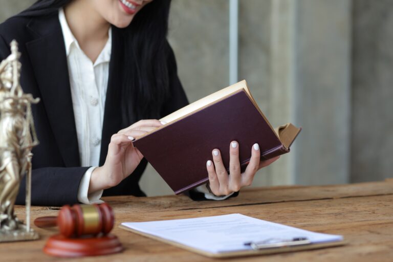 Charming young woman lawyer is reading a law book and working at a desk in a law firm.