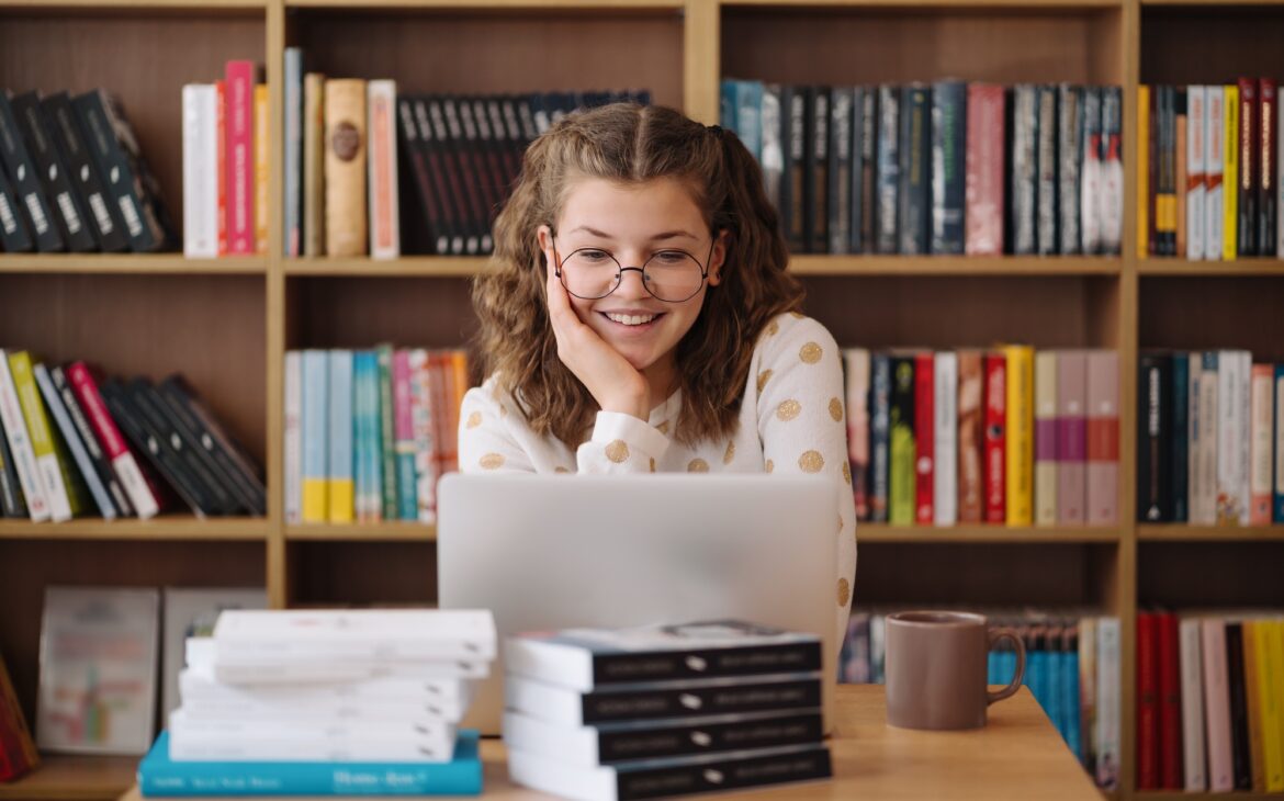 Girl studying among books using laptop
