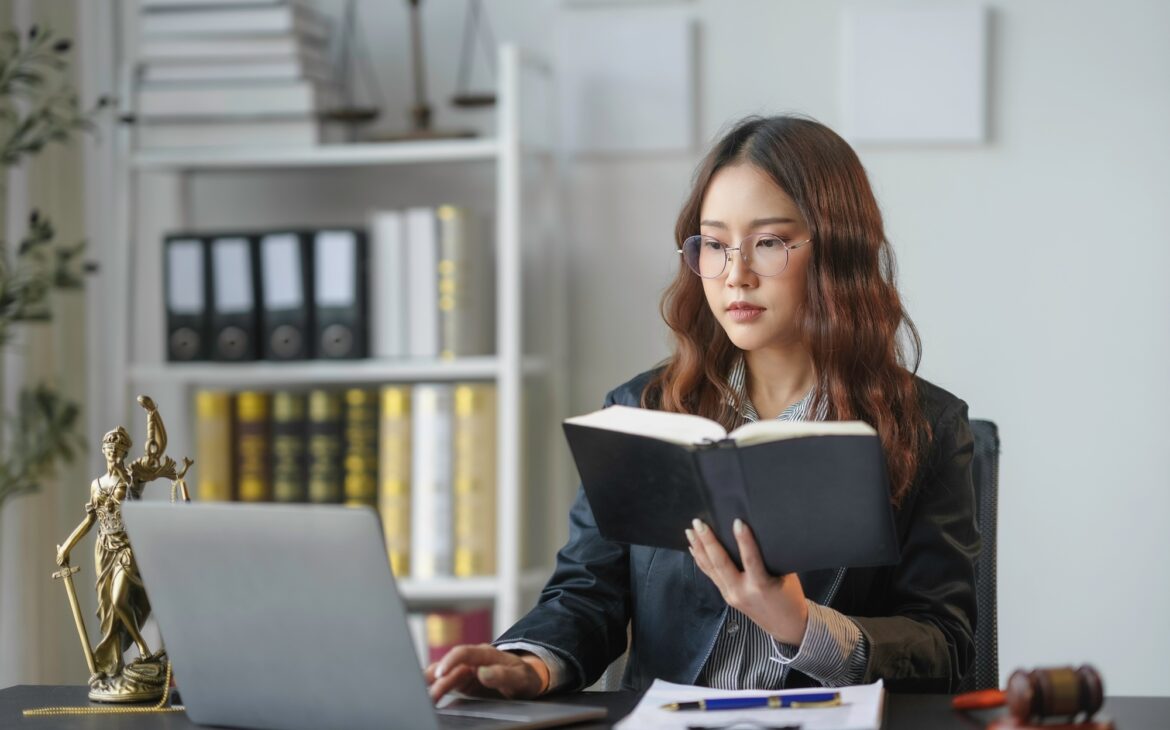 Lawyer working on laptop and reading law book in office