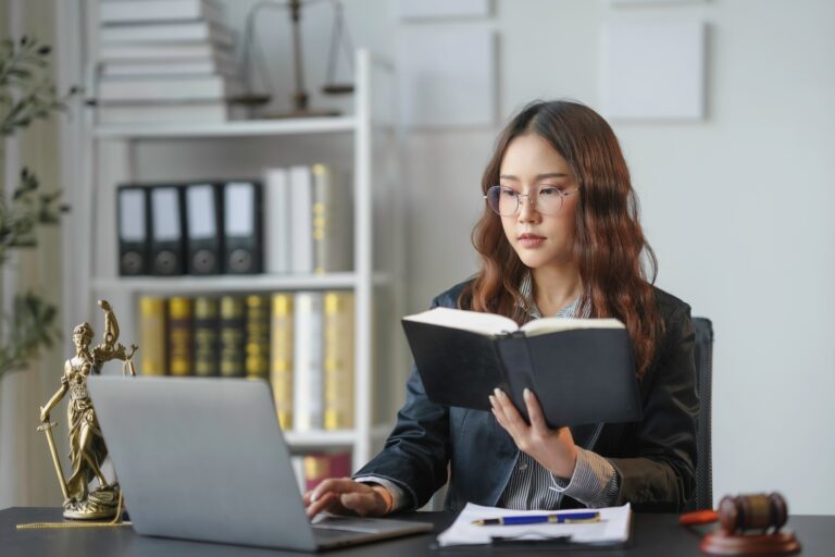 Lawyer working on laptop and reading law book in office
