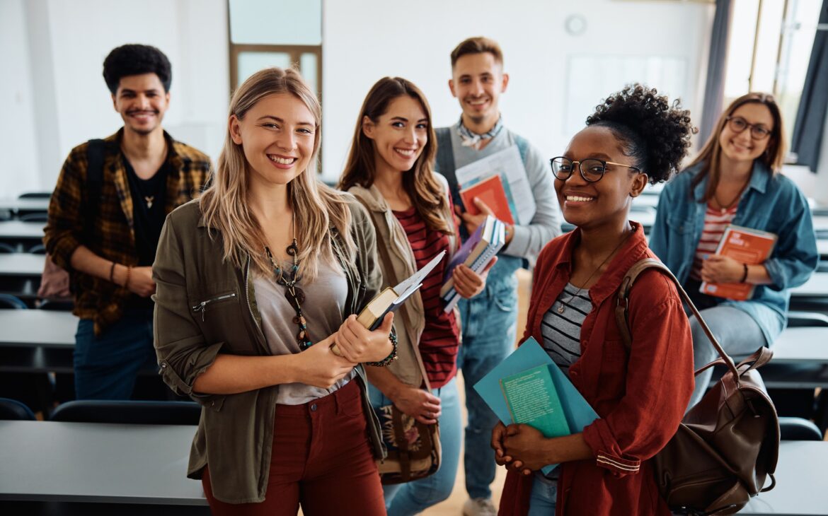Multi-ethnic group of university students in lecture hall looking at camera.