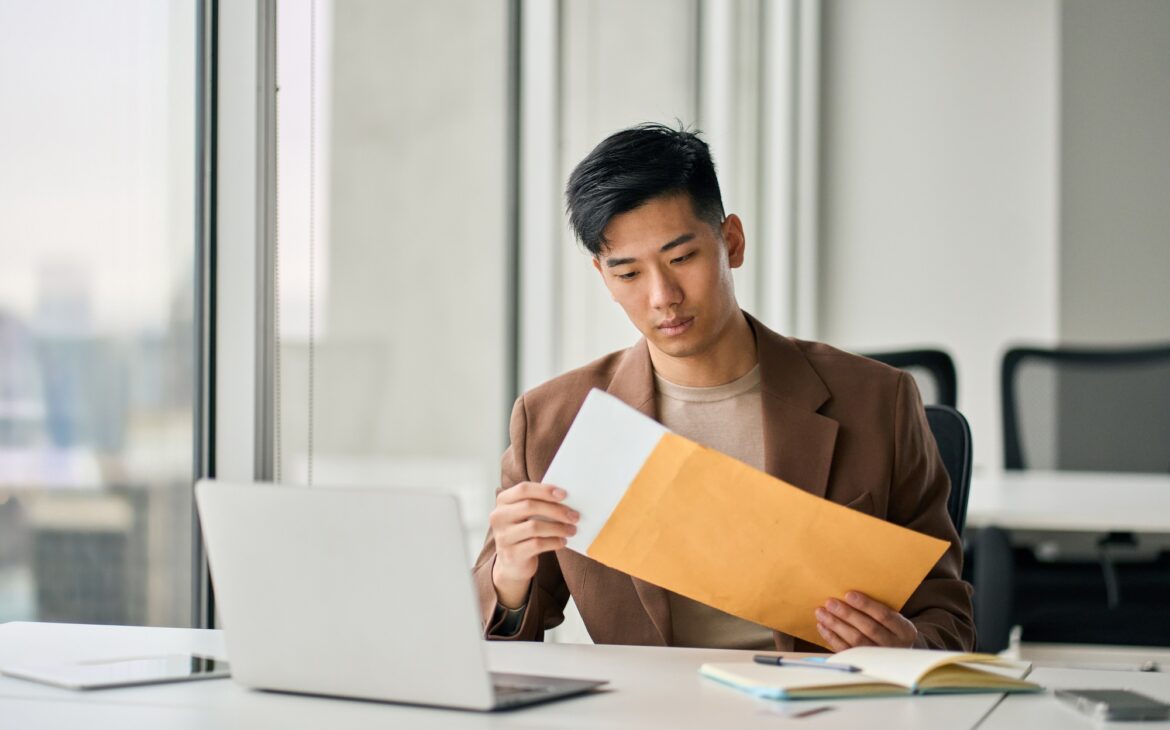 Young Asian professional business man receiving business mail letter in office.